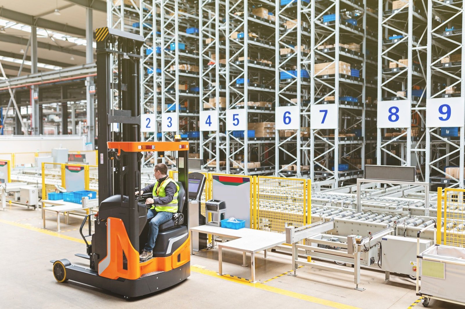 Storehouse employee in uniform working on reachtruck in modern automatic warehouse.