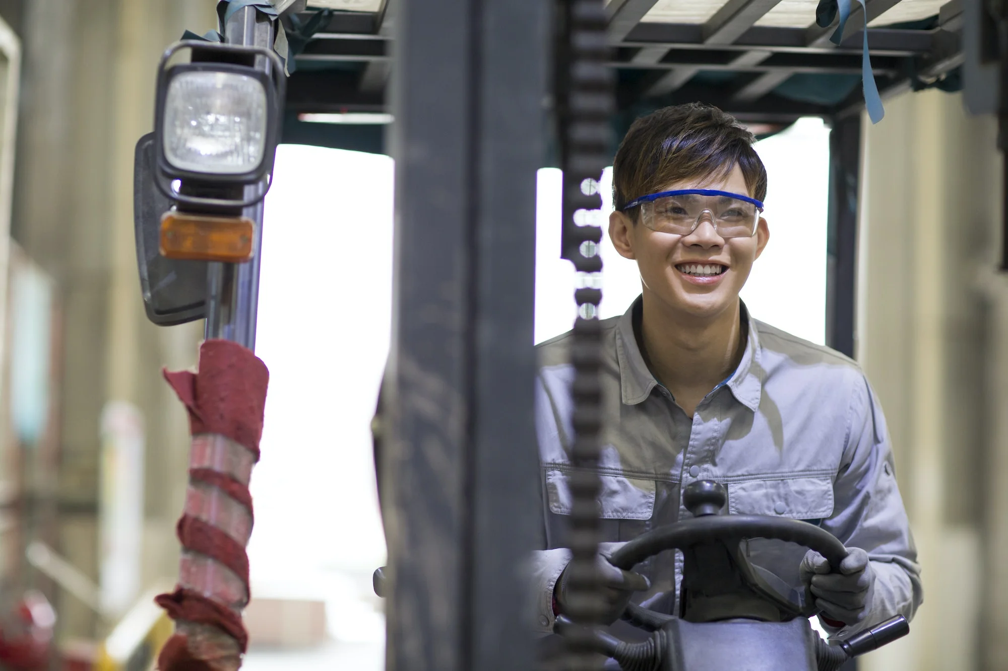 Young workman driving forklift in the factory